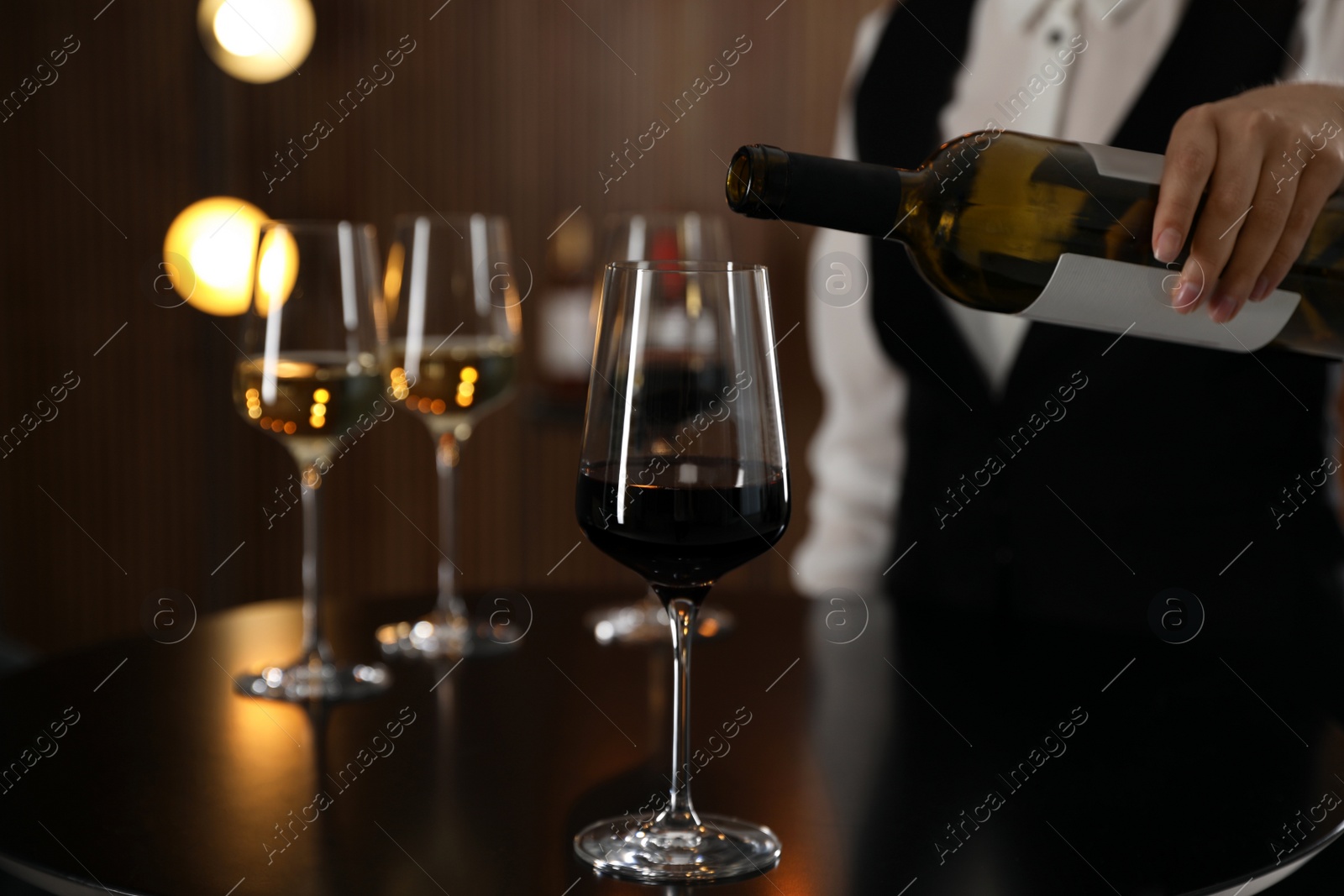Photo of Waitress pouring wine into glass in restaurant, closeup