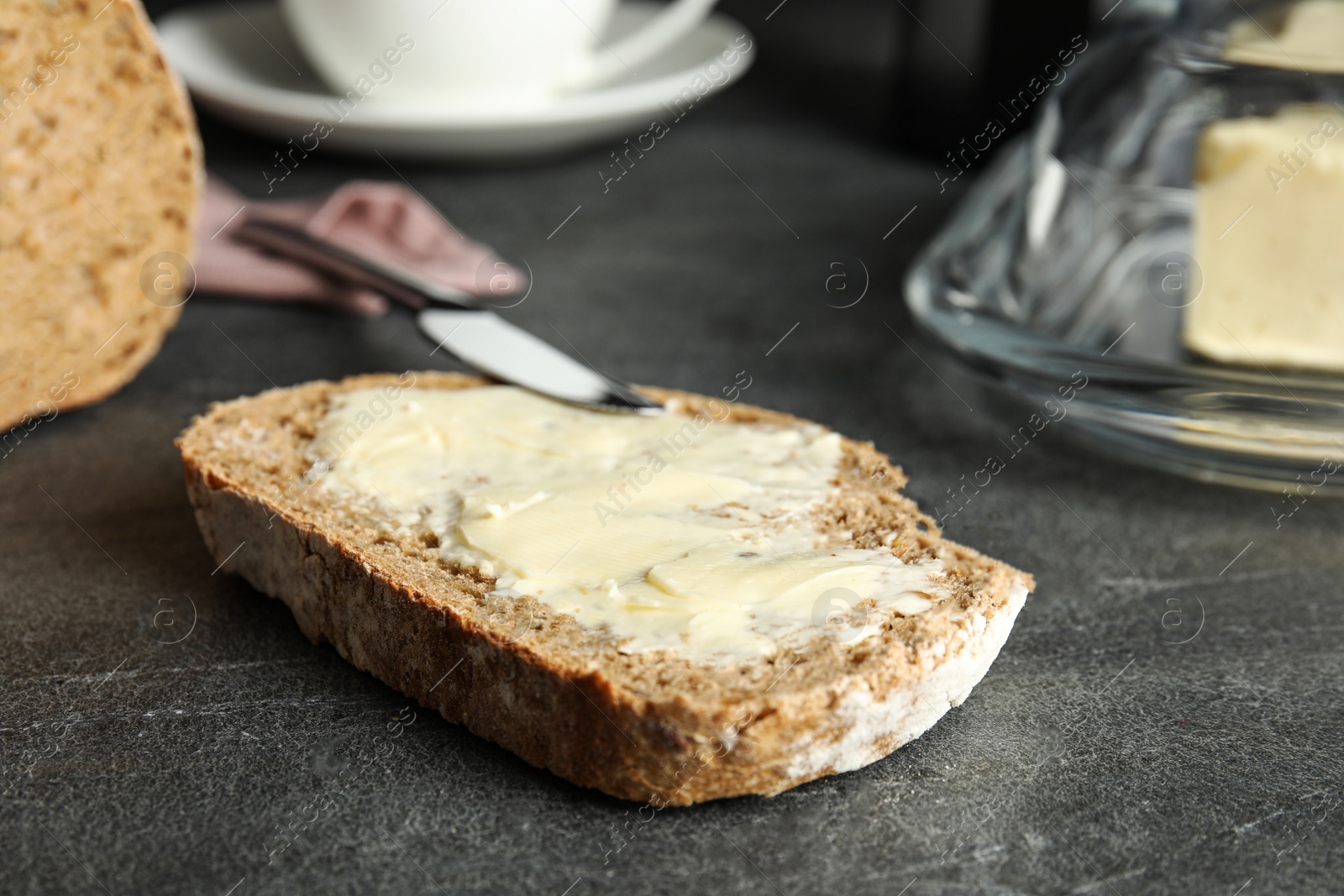 Photo of Slice of tasty bread with butter on dark table