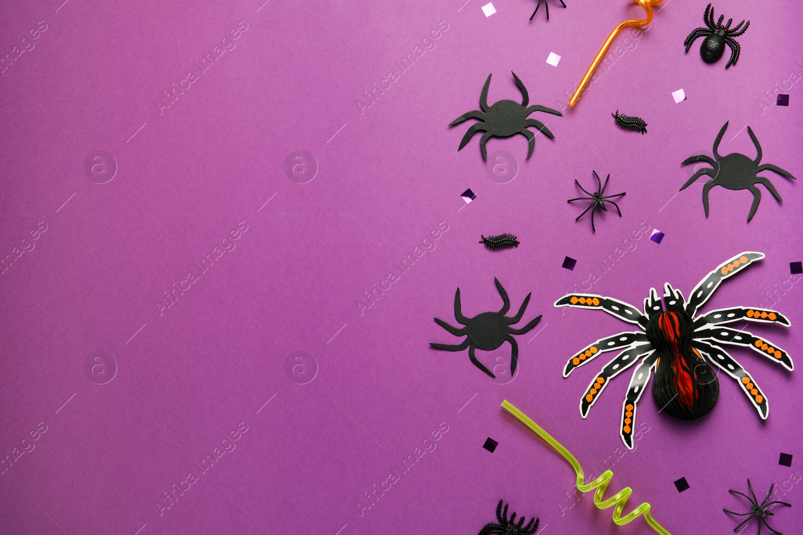 Photo of Flat lay composition with spiders, confetti and straws on purple background, space for text. Halloween celebration