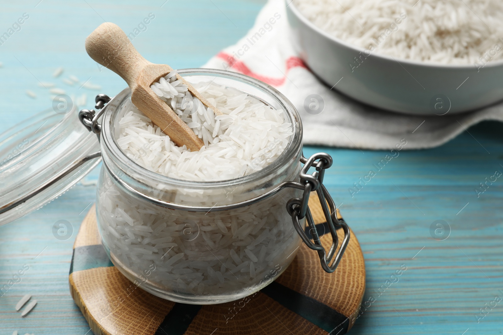 Photo of Raw basmati rice in jar on light blue wooden table, closeup