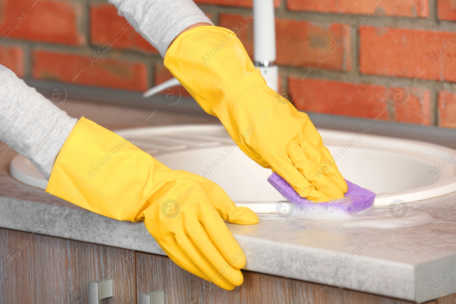 Photo of Woman cleaning kitchen sink with sponge, closeup