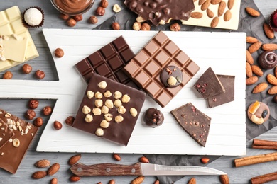 Flat lay composition with different delicious chocolate bars and nuts on table