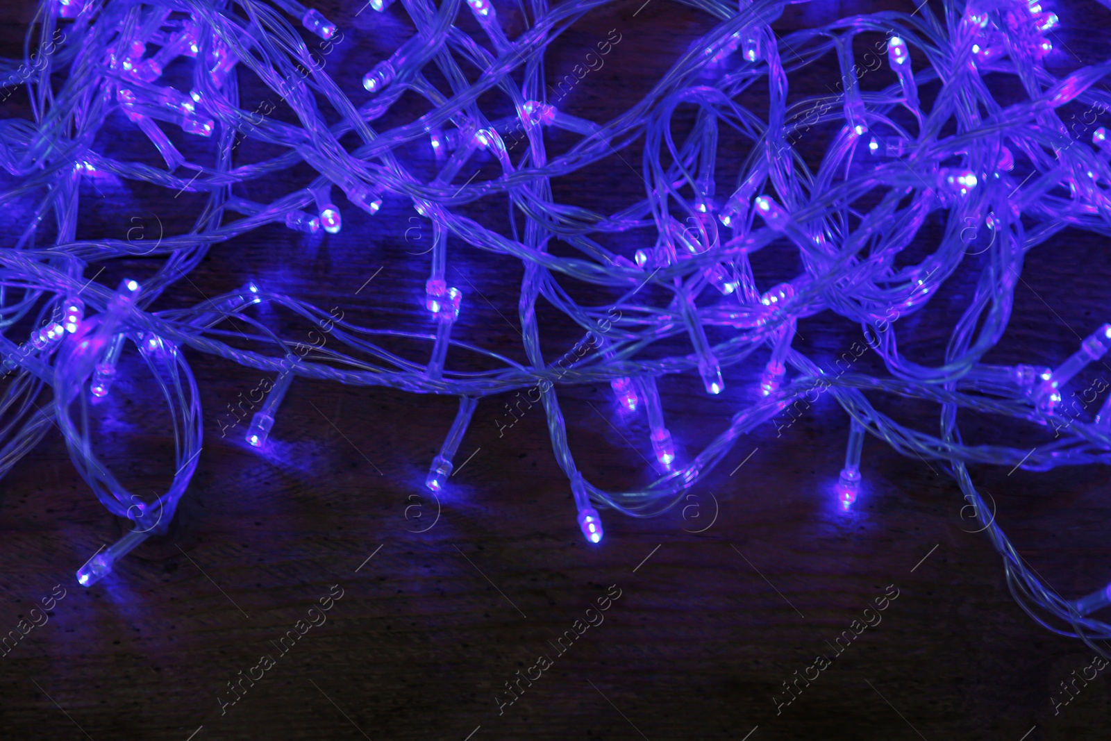 Photo of Blue Christmas lights on wooden background, top view