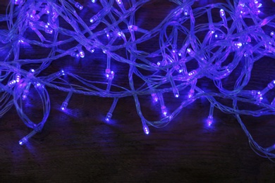 Blue Christmas lights on wooden background, top view