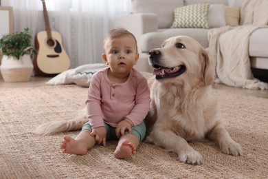 Cute little baby with adorable dog on floor at home