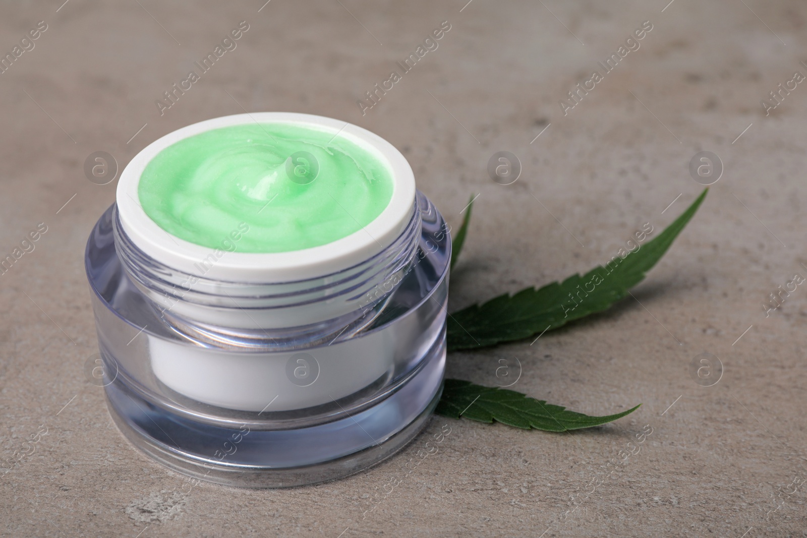 Photo of Jar of hemp cream and leaf on light table, closeup. Natural cosmetics