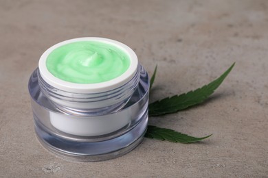 Photo of Jar of hemp cream and leaf on light table, closeup. Natural cosmetics