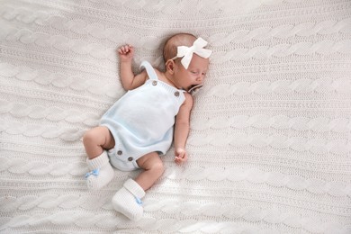 Photo of Adorable newborn baby with pacifier sleeping on white knitted plaid, top view. Space for text