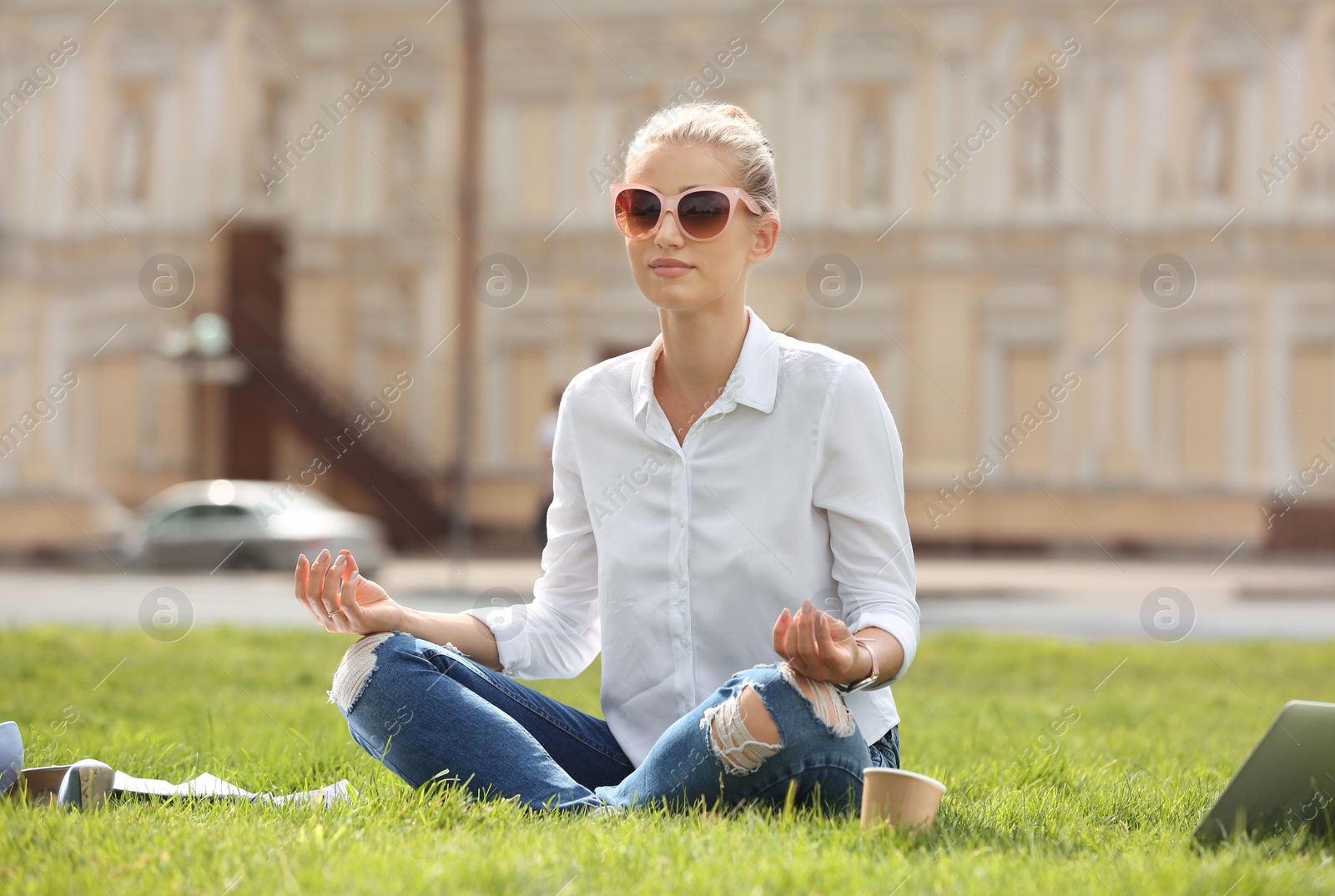 Photo of Young woman meditating on green lawn in park. Joy in moment