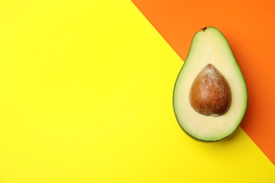 Cut fresh ripe avocado on color background, top view with space for text