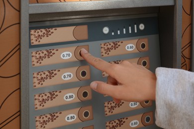 Using coffee vending machine. Woman pressing button to choose drink, closeup