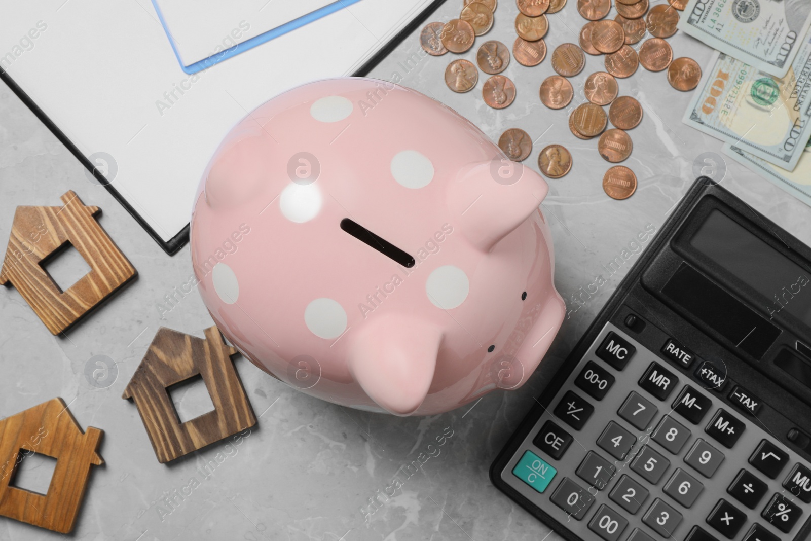 Photo of Flat lay composition with piggy bank, coins and wooden house models on grey marble table