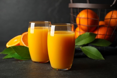 Glasses of orange juice and fresh fruits on black table