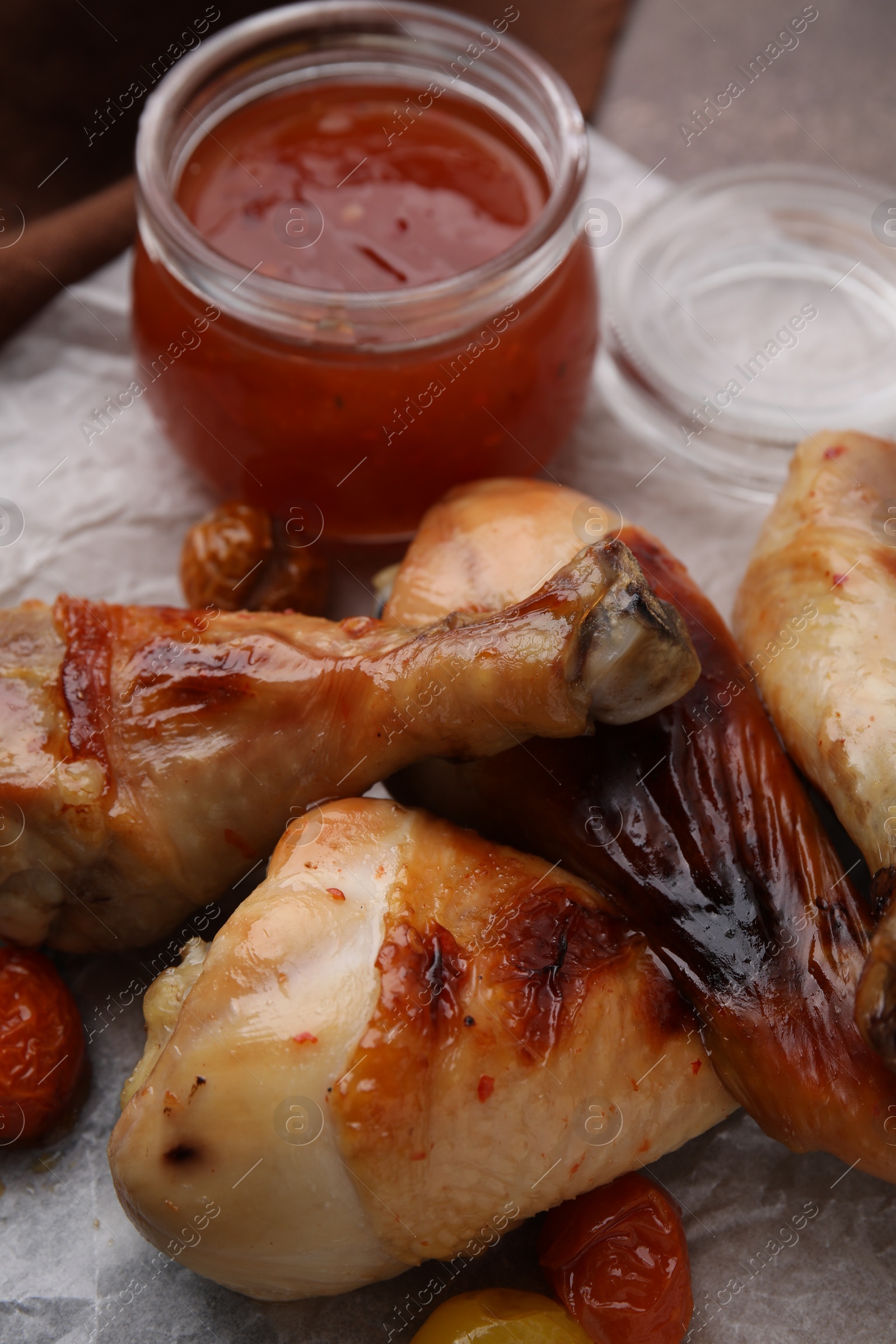 Photo of Marinade, roasted chicken drumsticks and tomatoes on brown table, closeup