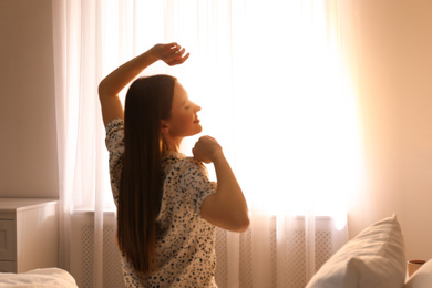 Photo of Young woman stretching on bed at home. Lazy morning