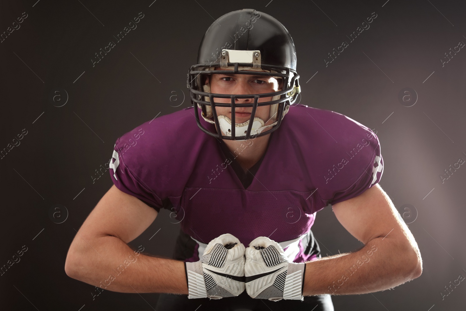 Photo of American football player wearing uniform on dark background