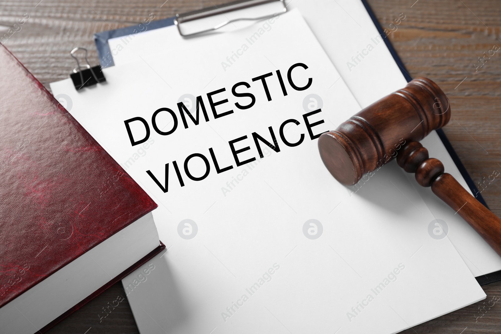 Photo of Clipboard with words DOMESTIC VIOLENCE and gavel on wooden table