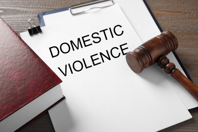 Photo of Clipboard with words DOMESTIC VIOLENCE and gavel on wooden table