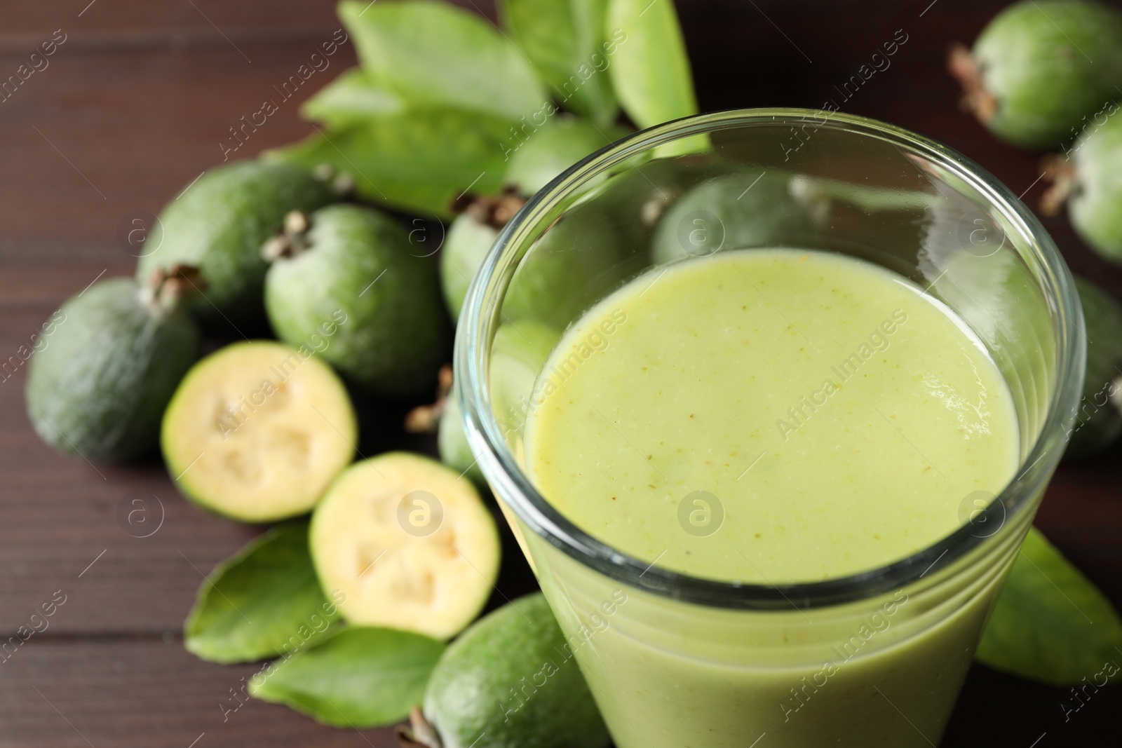 Photo of Fresh feijoa smoothie in glass on wooden table, closeup