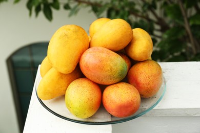 Delicious ripe yellow mangoes on glass plate outdoors