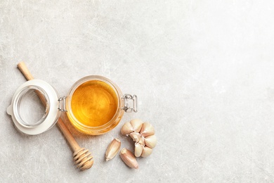 Photo of Jar with honey and garlic as cold remedies on table, top view