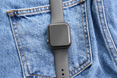 Photo of Stylish smart watch on jeans, top view