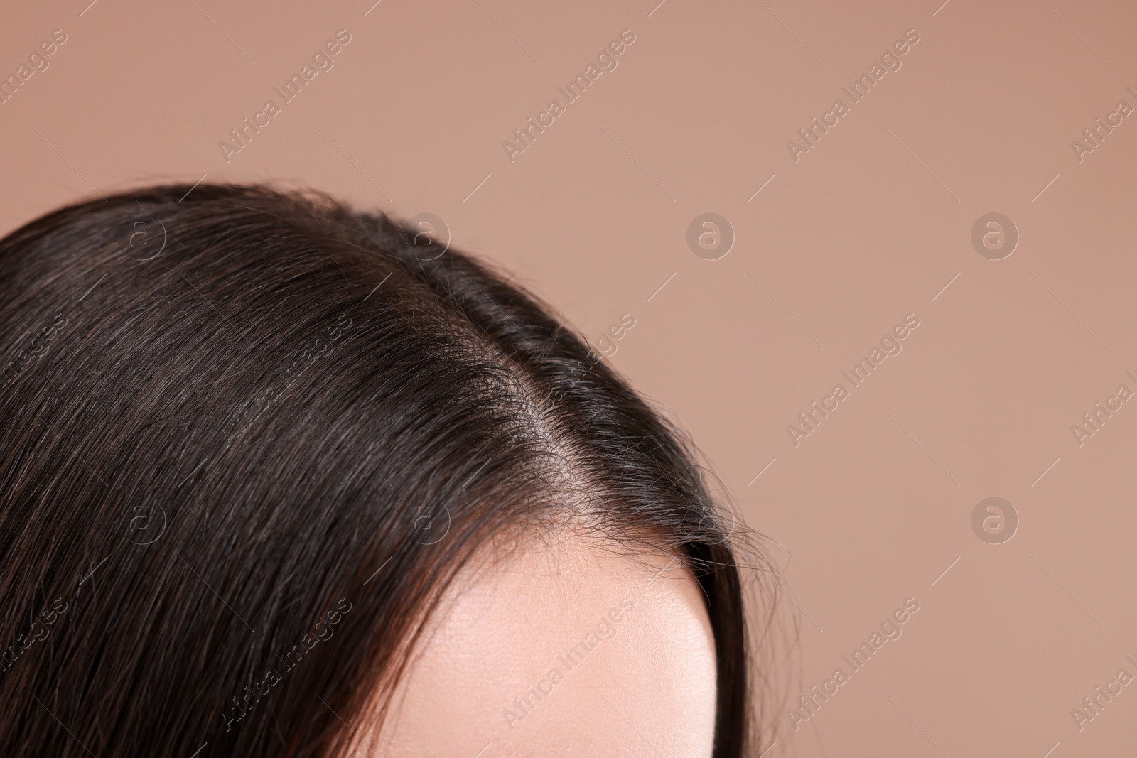 Photo of Woman with healthy dark hair on beige background, closeup. Space for text