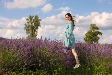 Photo of Beautiful woman with basket in lavender field. Space for text