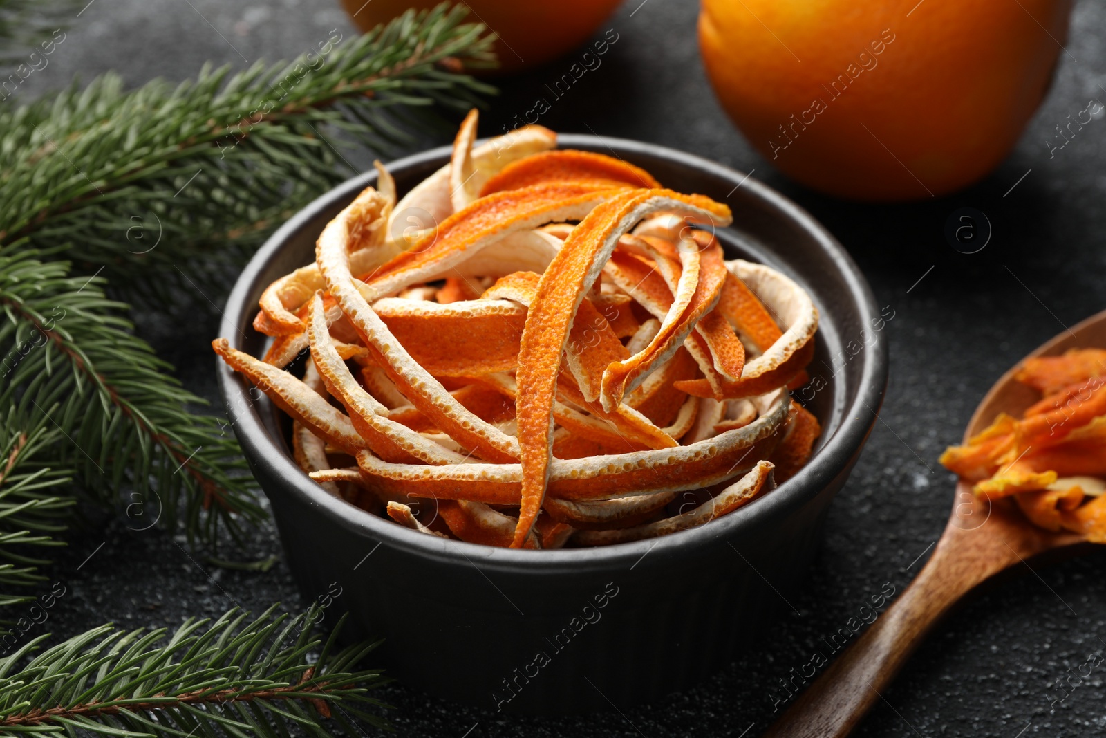 Photo of Dry peels, oranges and fir branch on gray textured table, closeup