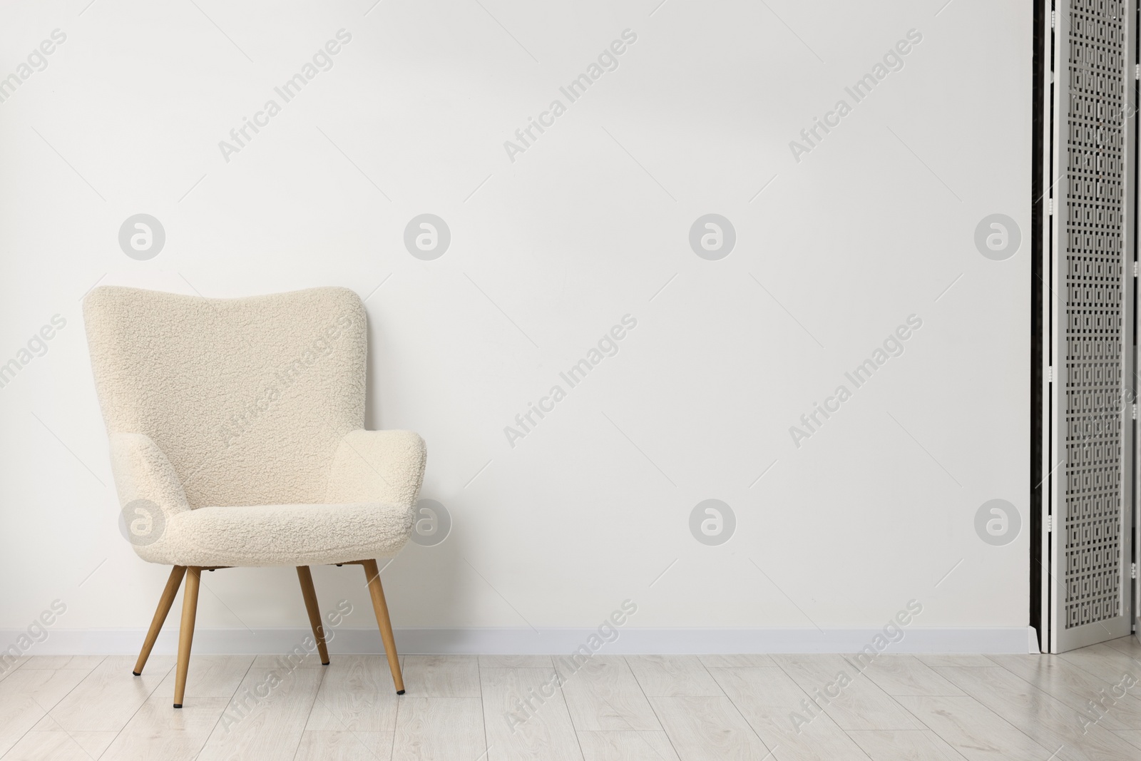 Photo of Comfortable armchair near white wall in room, space for text