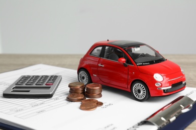 Photo of Toy car, money, calculator and insurance contract on table