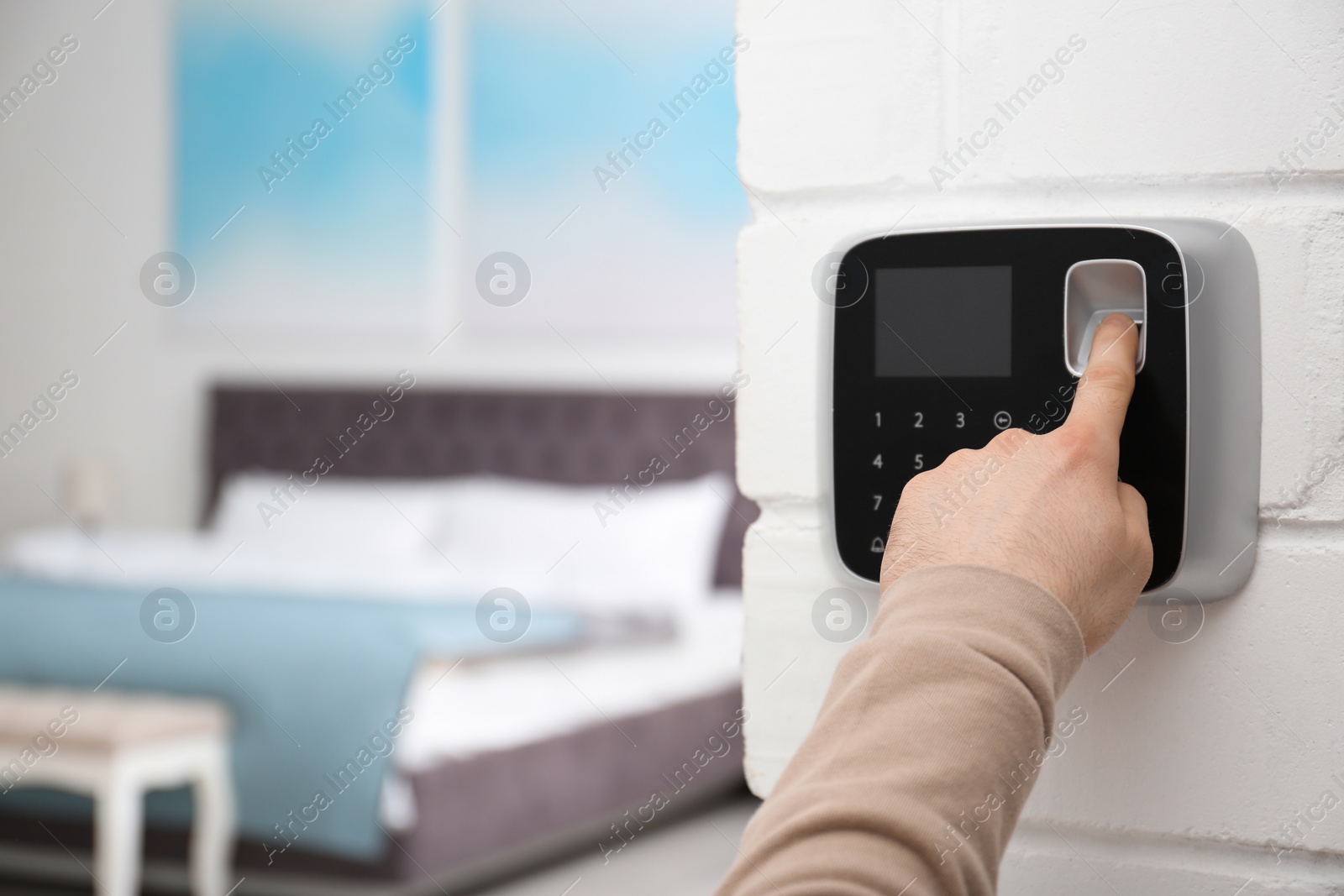 Photo of Man scanning fingerprint on alarm system at home, closeup. Space for text
