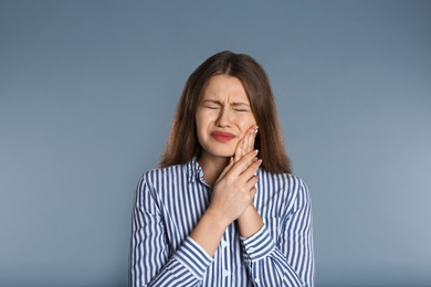 Photo of Woman suffering from toothache on grey background