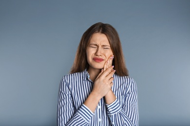 Woman suffering from toothache on grey background