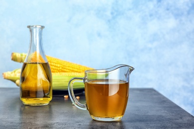 Photo of Jug of corn oil on table against color wall