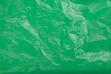 Photo of Crumpled green plastic bag as background, top view