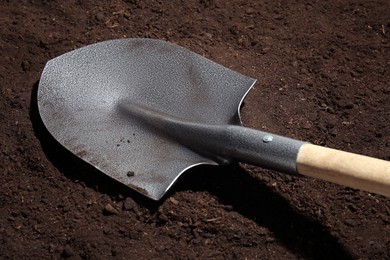 Photo of Metal shovel on fertile soil. Gardening tool
