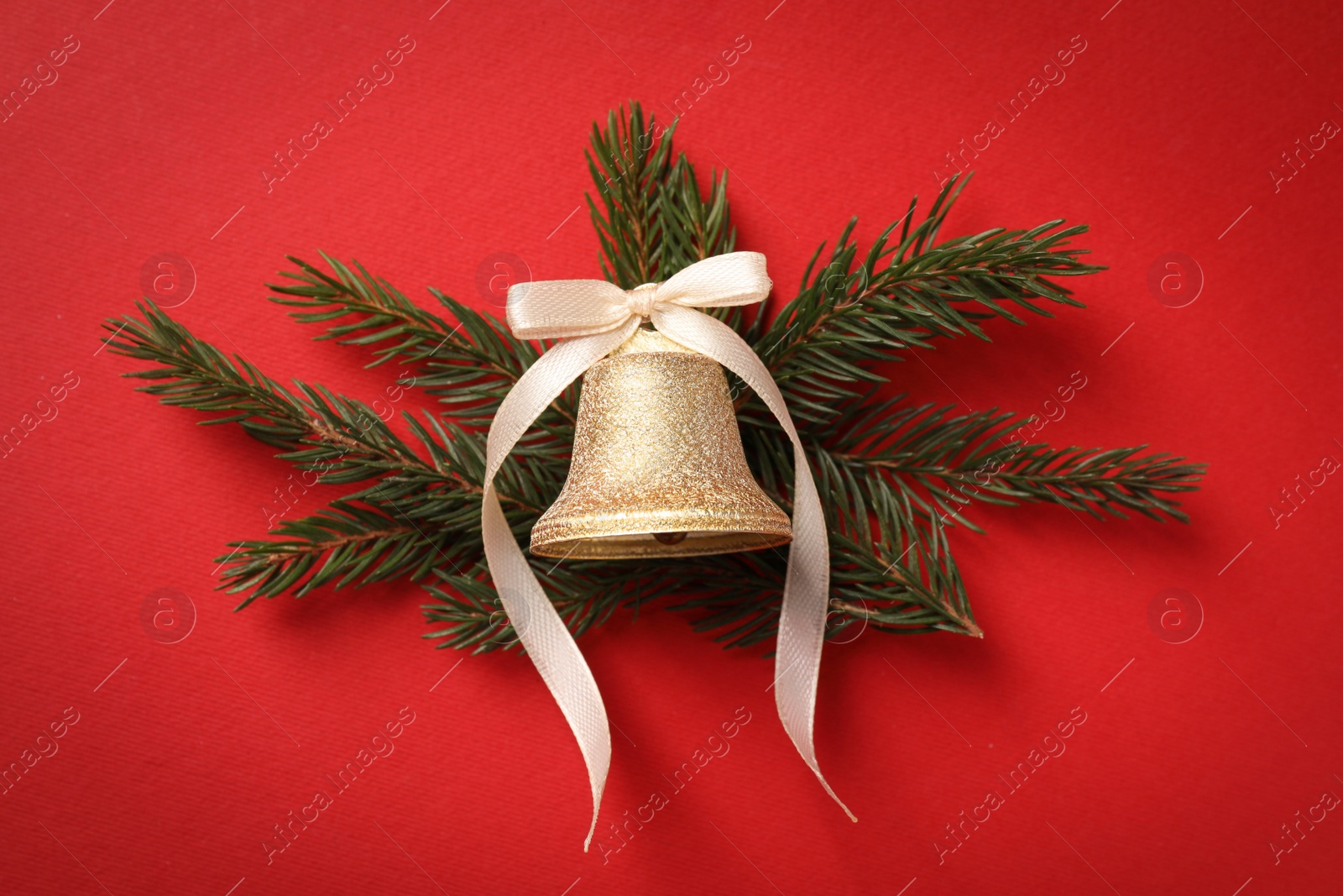 Photo of Bell with bow and fir branches on red background, flat lay. Christmas decor