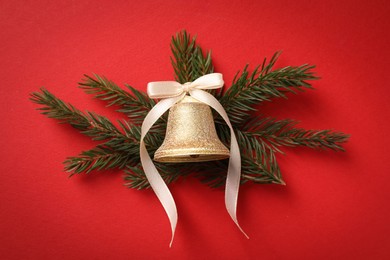 Photo of Bell with bow and fir branches on red background, flat lay. Christmas decor