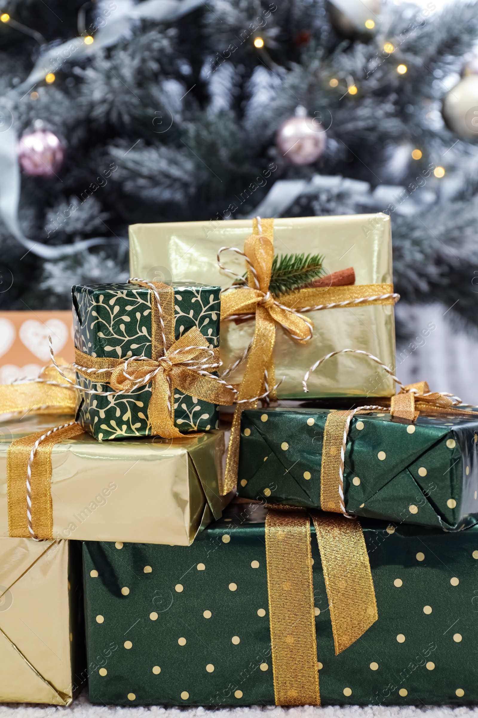 Photo of Many different gifts and blurred Christmas tree on background