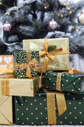 Photo of Many different gifts and blurred Christmas tree on background