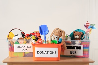 Photo of Donation boxes with different child toys on wooden table