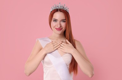 Photo of Beautiful young woman with tiara and ribbon on pink background
