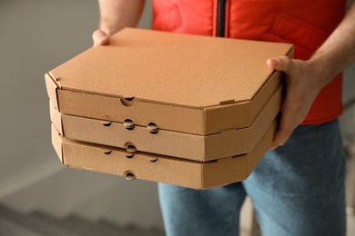 Man with pizza boxes indoors, closeup. Food delivery service