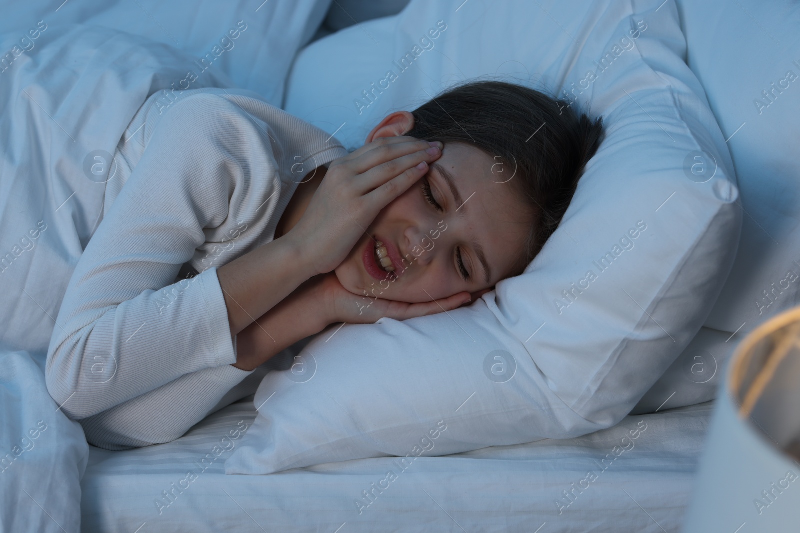 Photo of Little girl suffering from headache in bed at night