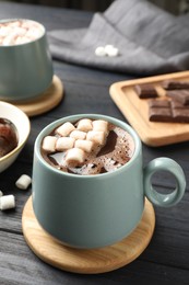 Cup of aromatic hot chocolate with marshmallows on dark gray wooden table, closeup