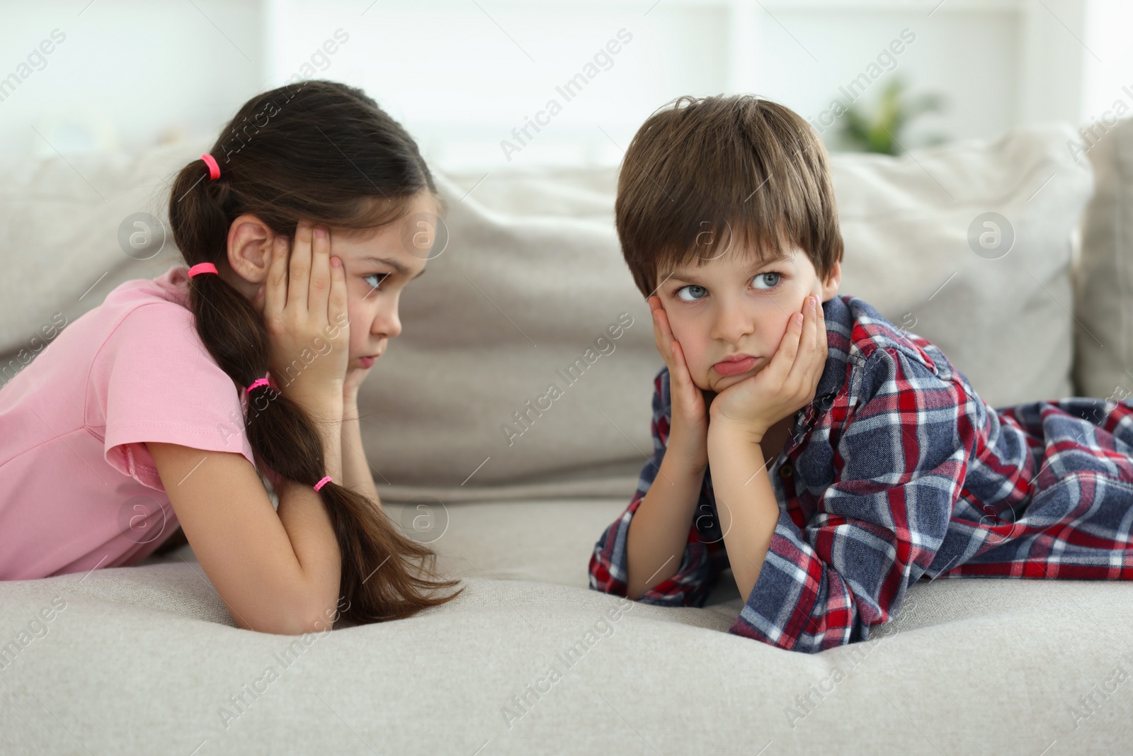 Photo of Upset brother and sister on sofa at home