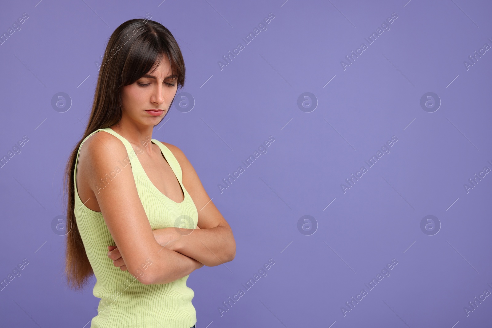 Photo of Resentful woman with crossed arms on violet background, space for text