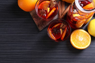 Photo of Aromatic punch drink and ingredients on black table, flat lay. Space for text