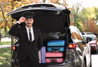 Young driver standing near car with open trunk outdoors